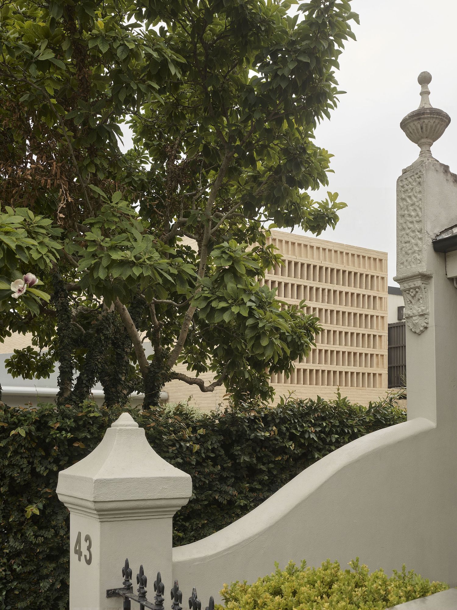 Clay House, Woollahra. The cream brick screen rising behind an original heritage fence.