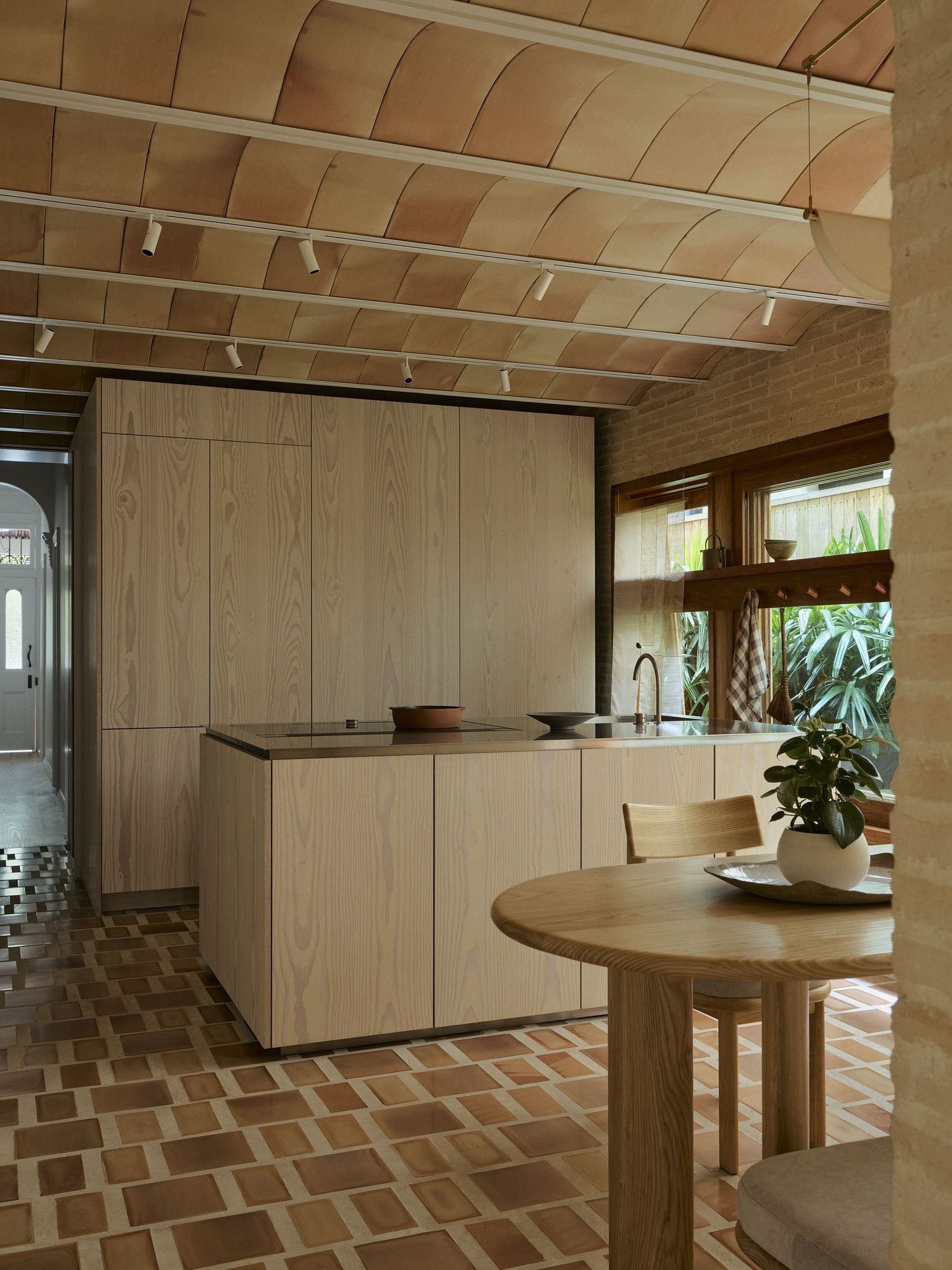 Clay House kitchen. Pale timber joinery under a vaulted terracotta ceiling.