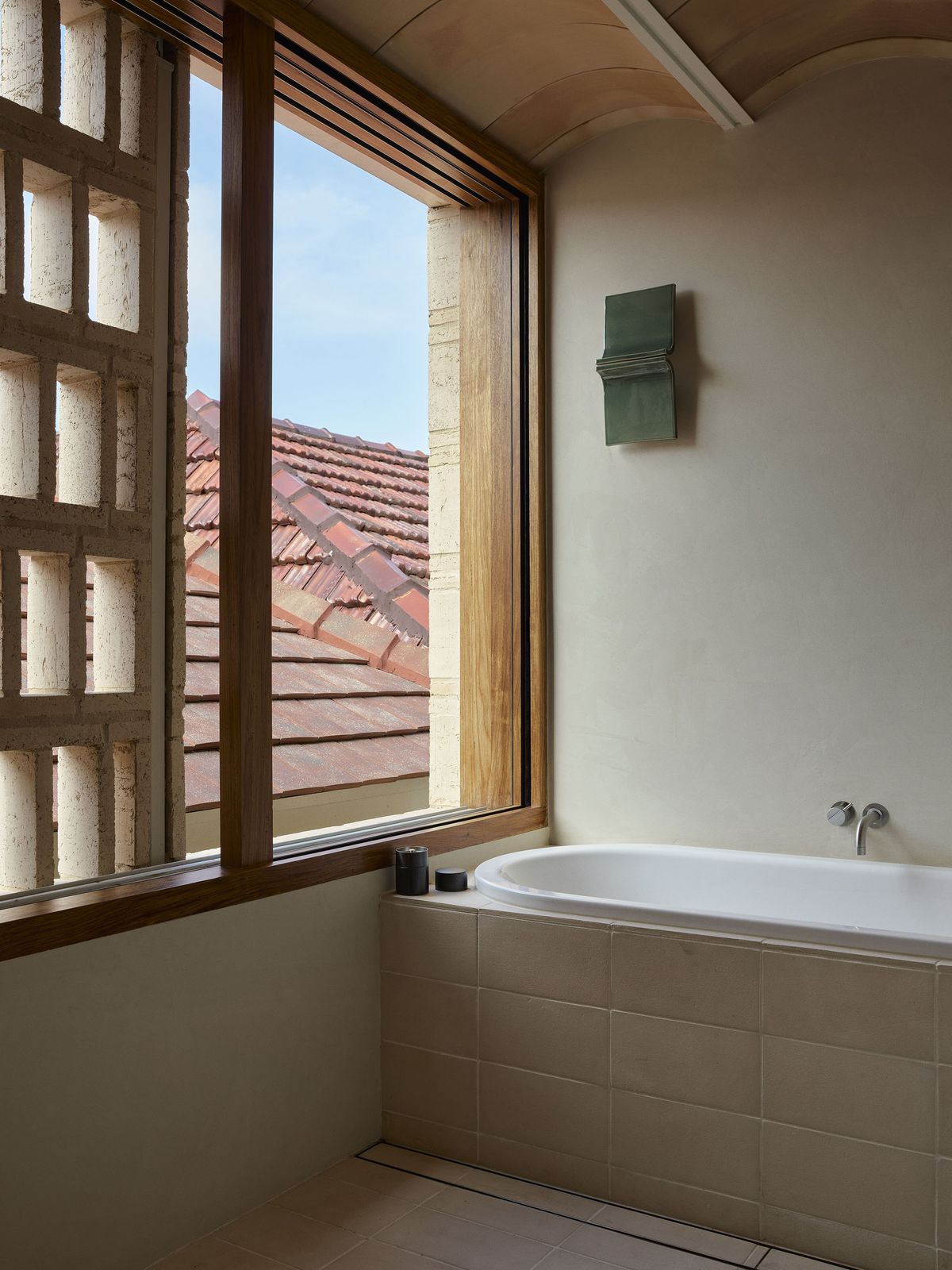 Clay House bathroom. Perforated brick screen filtering light beside the bath.
